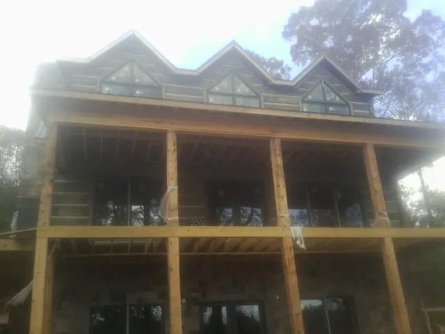 Dormers and porch framing on a large log home under construction — Roof Coating work by our crew in Carbonado