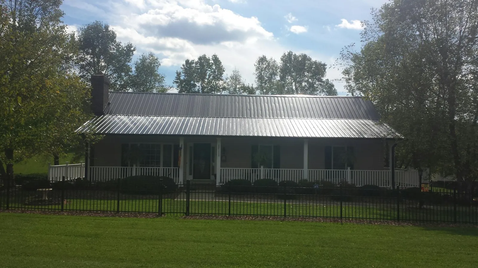 Gray metal roof on a brick ranch with a full width front porch — Gutter Guard Installation work by our crew in Carbonado