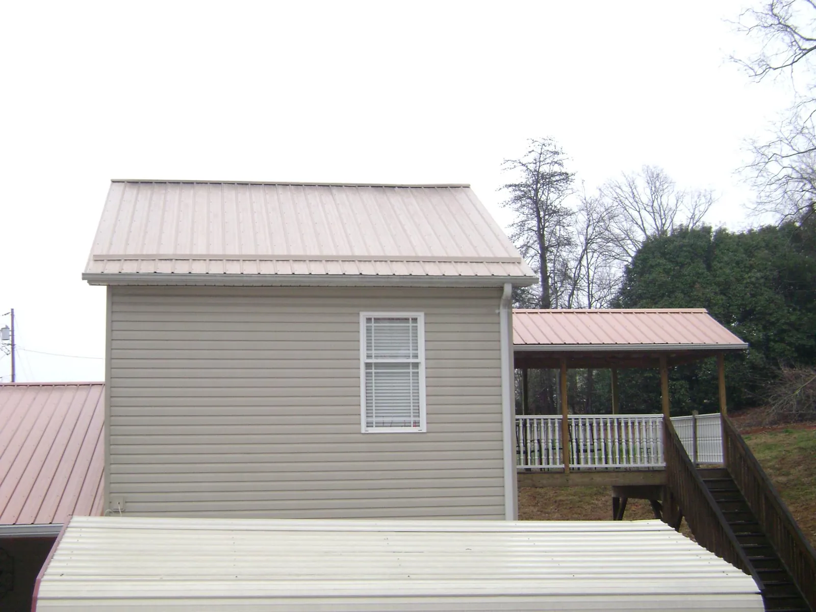 Tan metal roofs on a two story addition and attached porch, from a Roof Replacement job in Carbonado