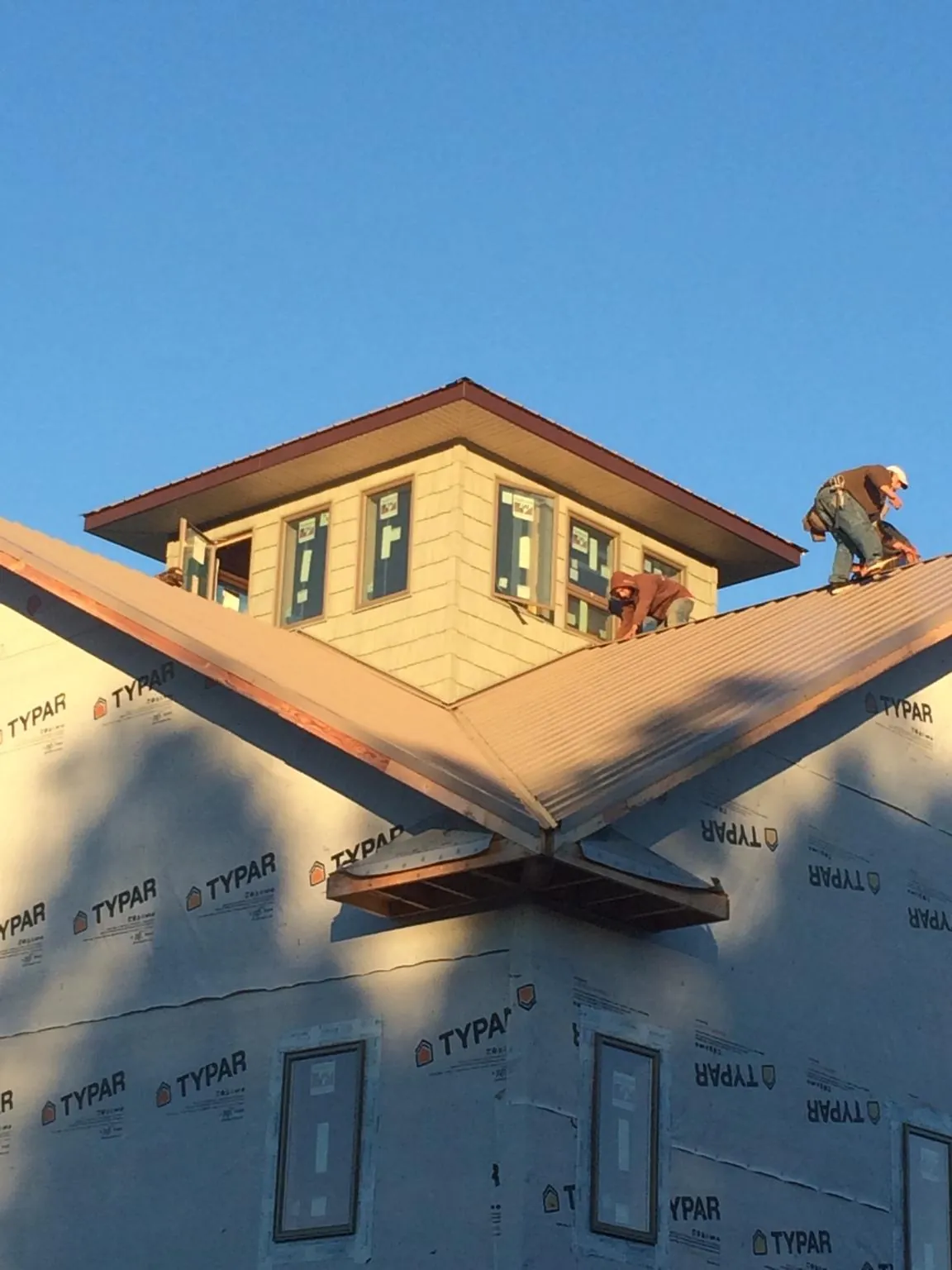 Roofers working around a rooftop cupola on a new metal roof at sunset — Roof Waterproofing in Carbonado by Roofing Brothers